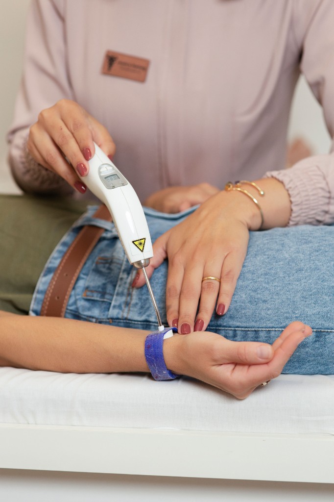 Fisioterapeuta aplicando laserterapia no punho de paciente